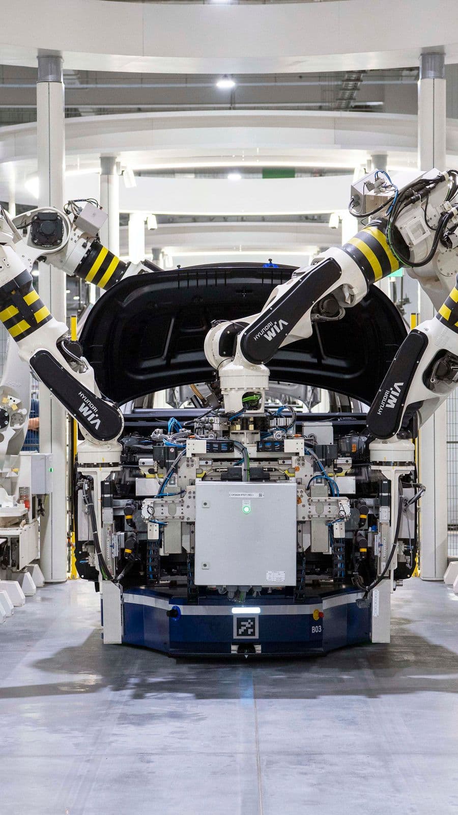 Braços robóticos montando a carroceria de um carro na linha de produção
